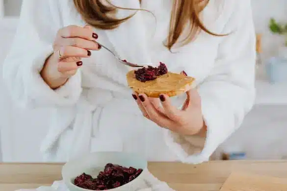 Cuillère de beurre de cacahuètes crémeux sur une tranche de pain complet, accompagnée d'amandes et de dattes