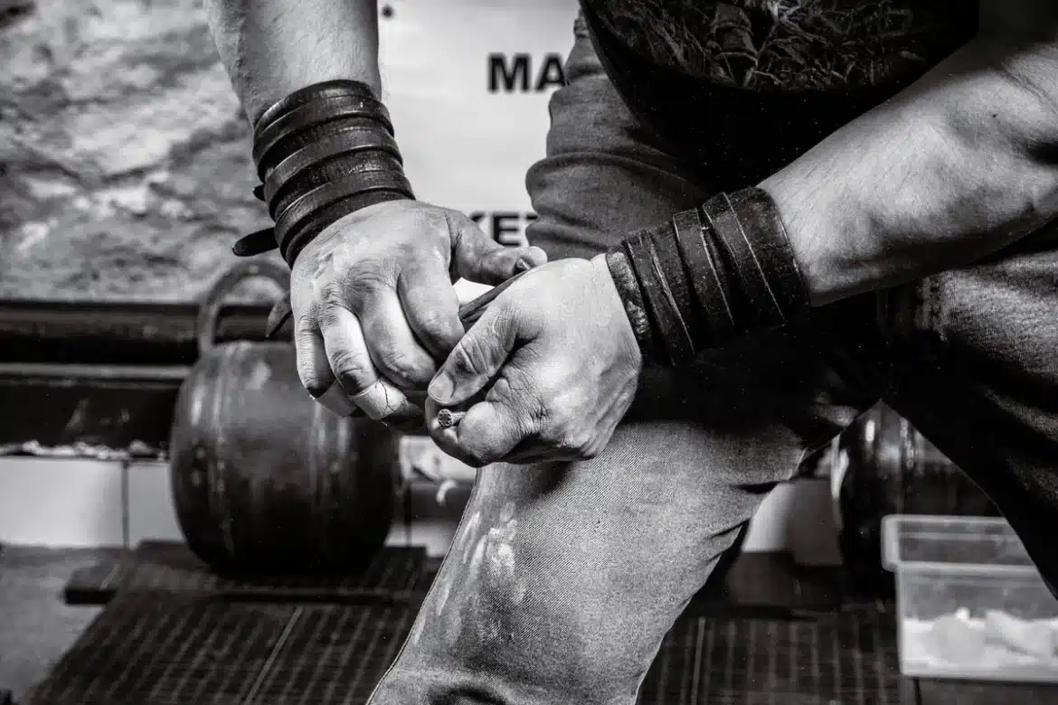 Mains préparant une barre de musculation dans une salle de sport, équipements de résistance en arrière-plan