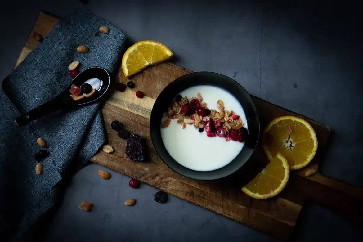 Bol de produit laitier crémeux avec cuillère, baies et amandes sur plan de travail