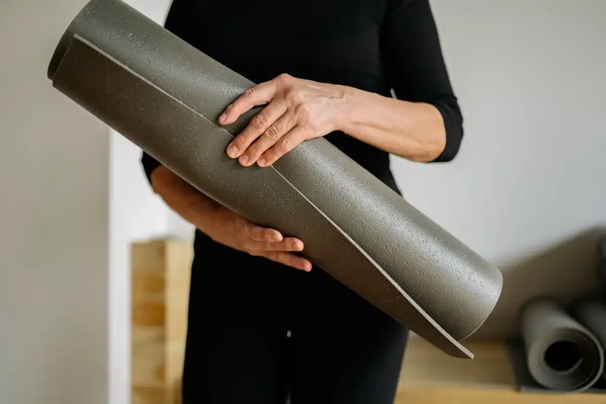 Pratiquant de yoga en posture dynamique, transpiration visible sur tapis antidérapant
