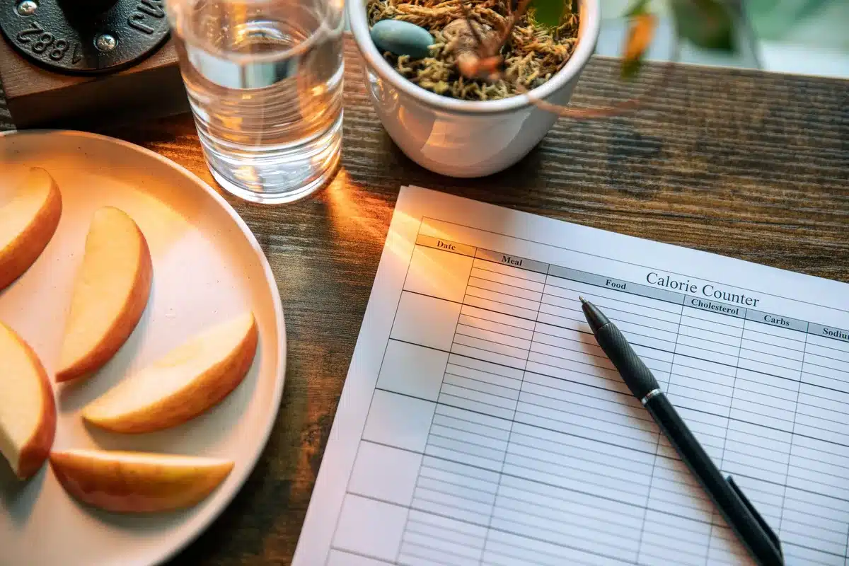 Carnet de suivi alimentaire et balance pour noter ses apports caloriques quotidiens