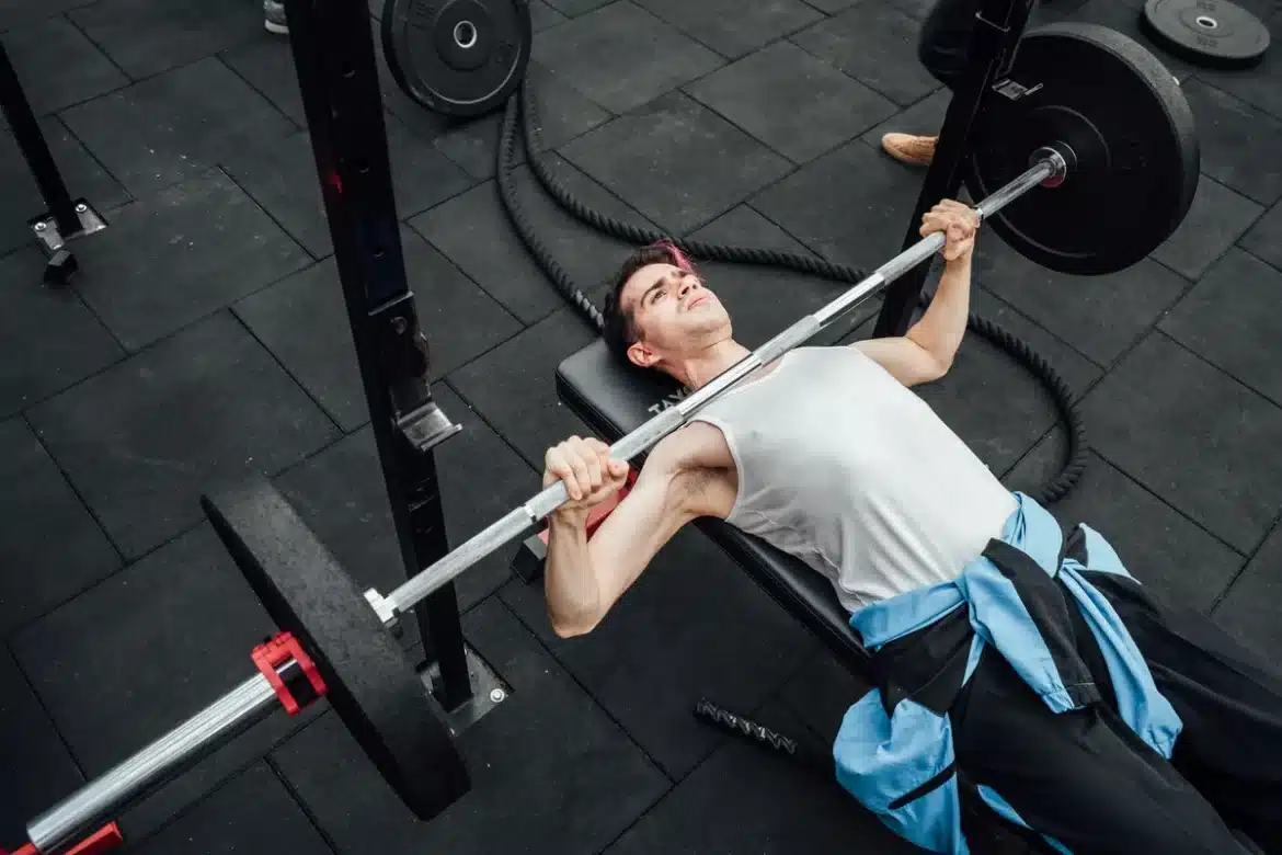 Mains saisissant une barre de musculation, épaules rétractées, poitrine préparée pour le développé couché