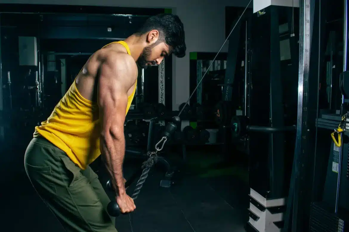 Personne effectuant une extension triceps à la poulie dans une salle de musculation