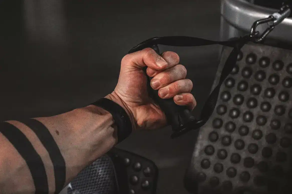 Personne portant une combinaison d'électrostimulation réalisant des squats guidés par un coach en salle