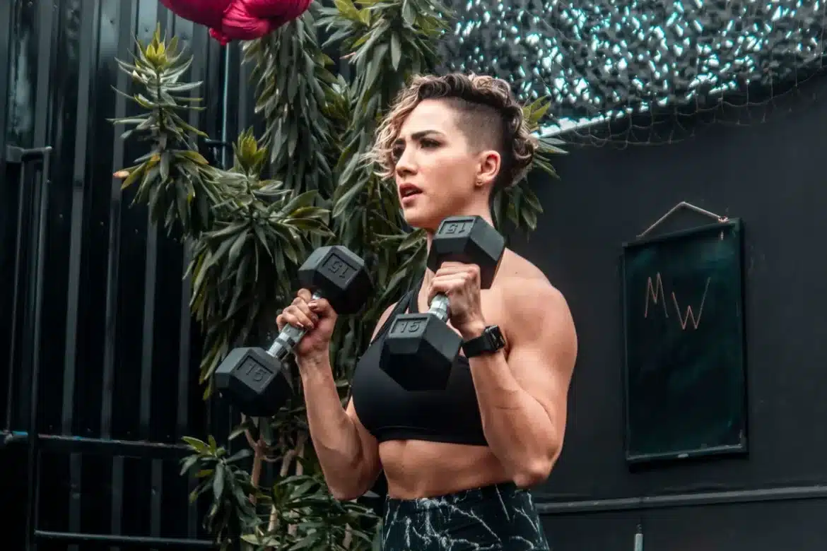 Femme effectuant un exercice d'haltères en salle de sport, posture concentrée et contrôlée