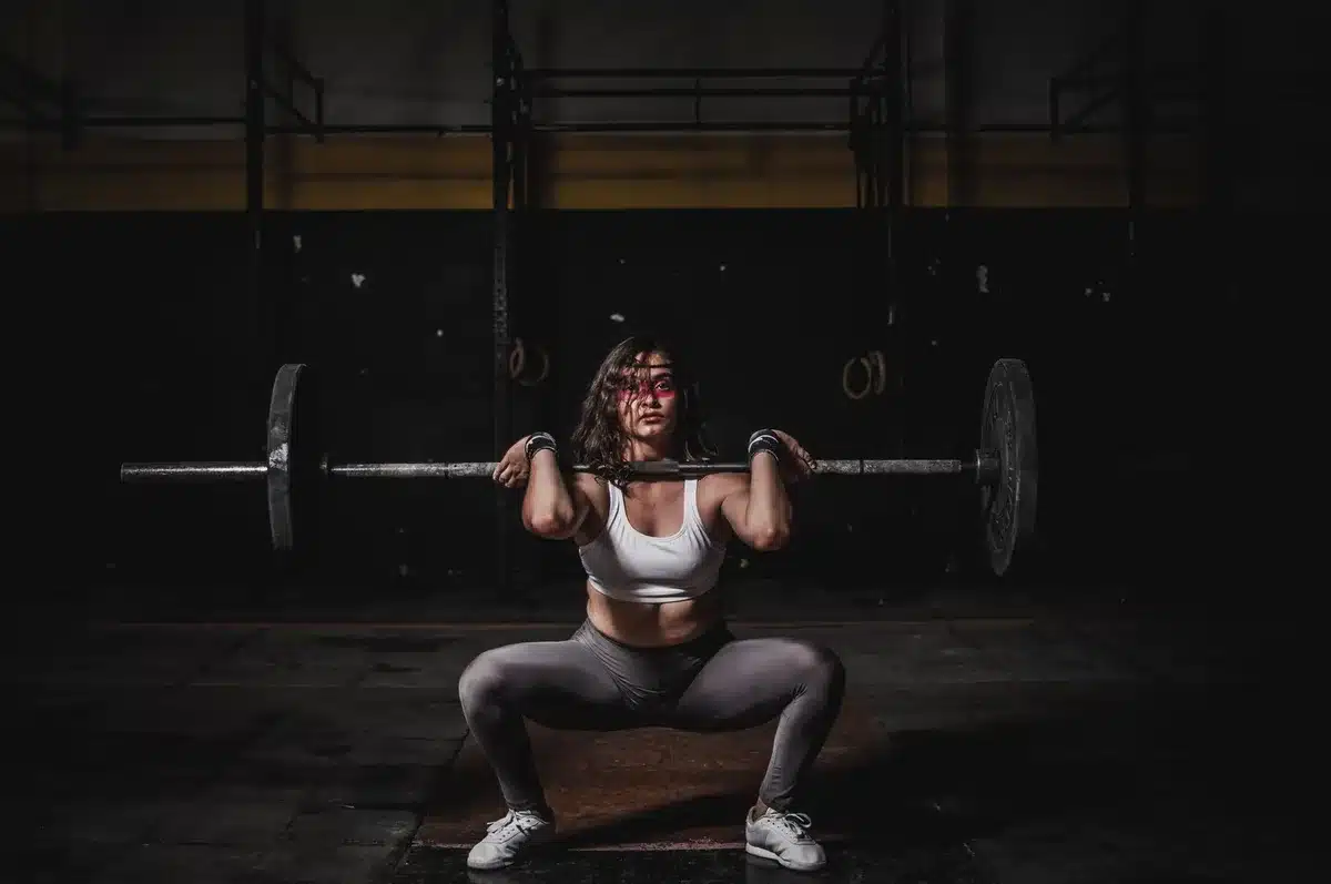 Femme effectuant un squat à la barre dans une salle de musculation