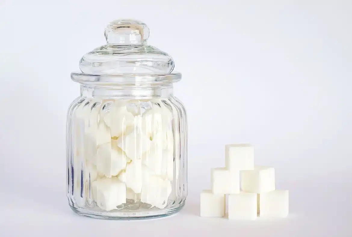 Sachet d'édulcorant sans calories posé près d'un verre d'eau, symbolisant le sucralose