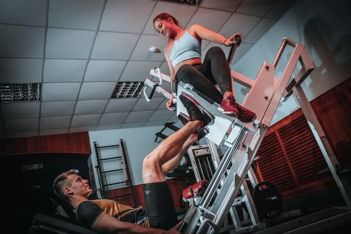 Athlète effectuant une répétition contrôlée à la presse à cuisses dans une salle de musculation.