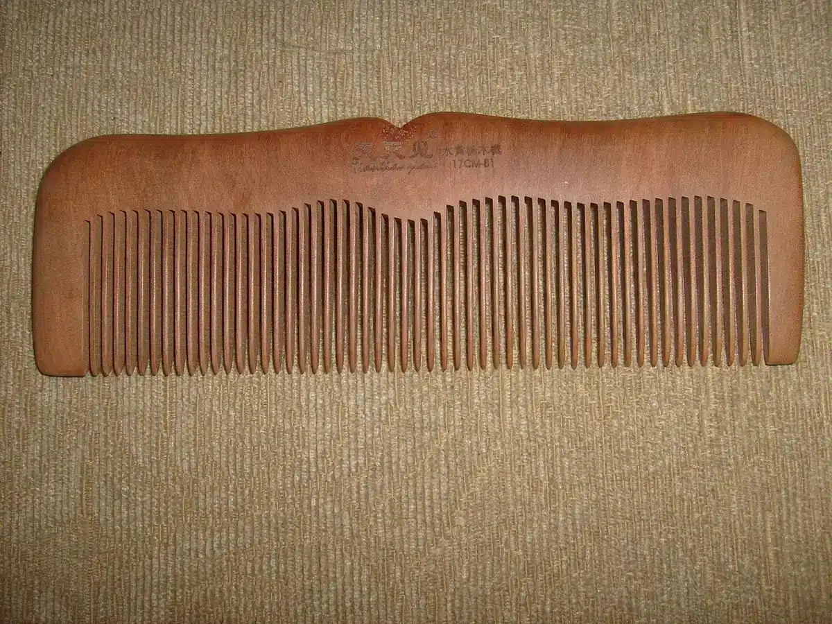 Peigne à dents fines et produit démêlant sur une surface de salle de bain
