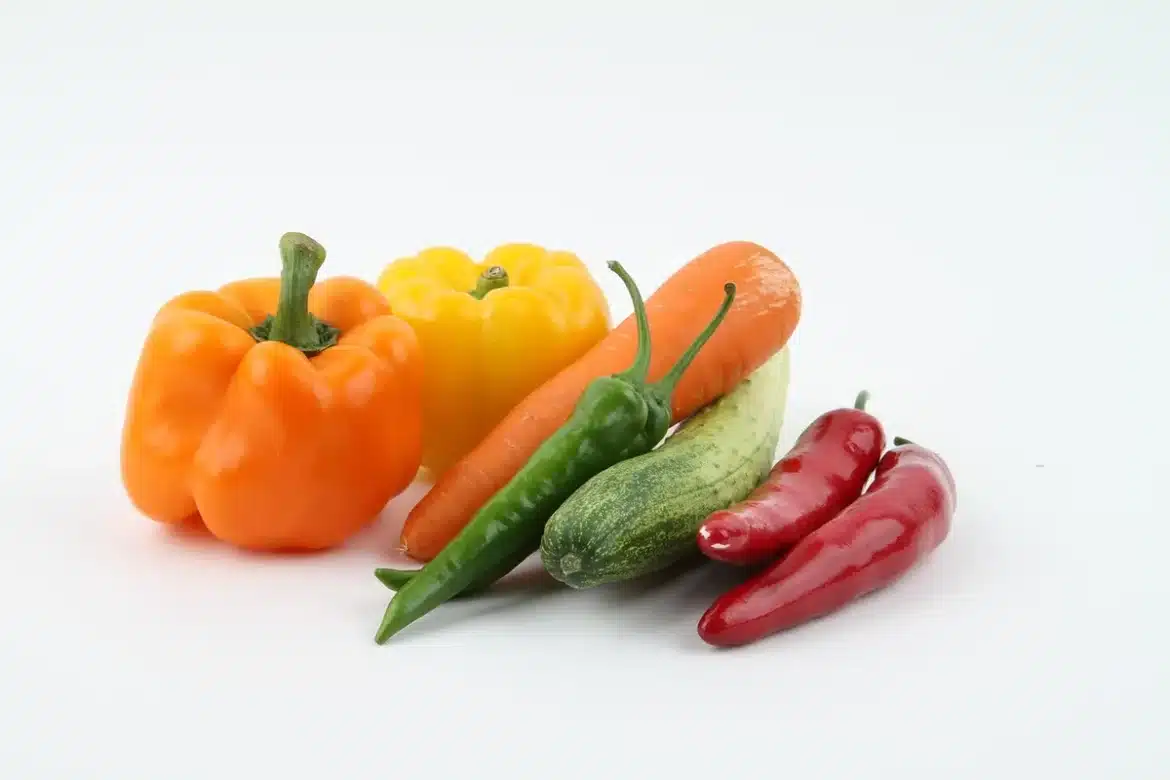 Poivrons rouges, jaunes et verts sur une planche de bois avec un couteau